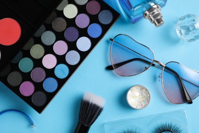 Photo of Set of makeup products and sunglasses on light blue background, flat lay