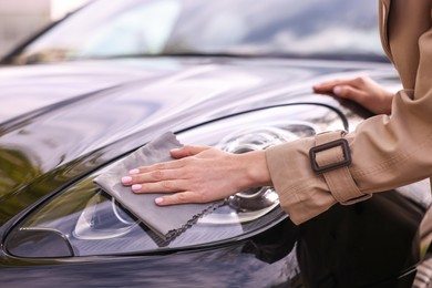 Woman wiping her modern car with rag, closeup