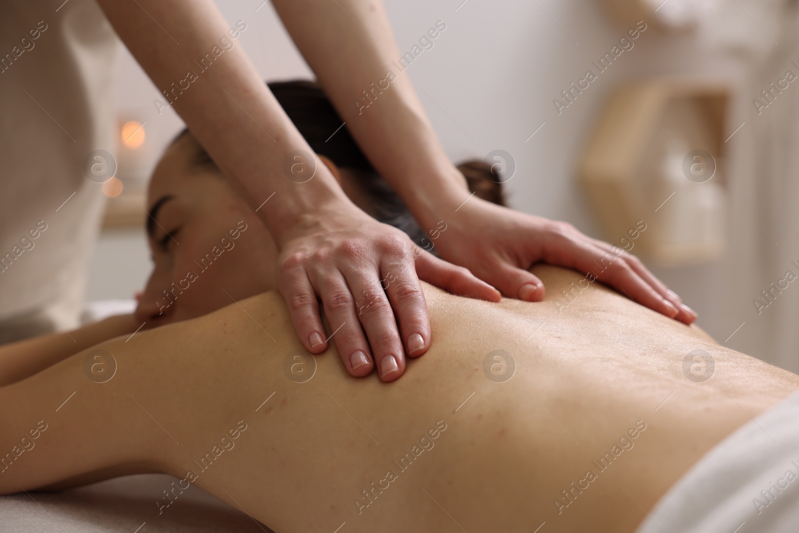 Photo of Woman receiving back massage in spa salon, focus on hands