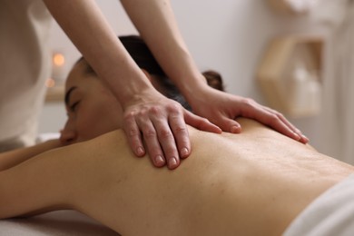 Photo of Woman receiving back massage in spa salon, focus on hands