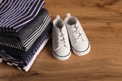 Photo of Stack of baby boy's clothes and shoes on wooden table