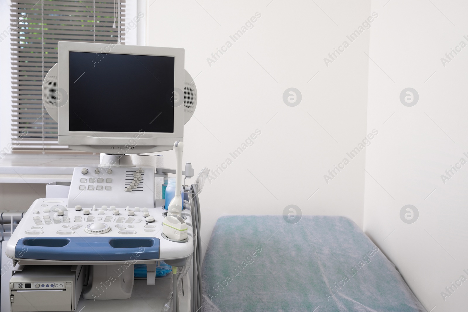 Photo of Ultrasound machine and examination table in hospital. Space for text