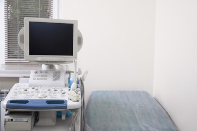 Photo of Ultrasound machine and examination table in hospital. Space for text