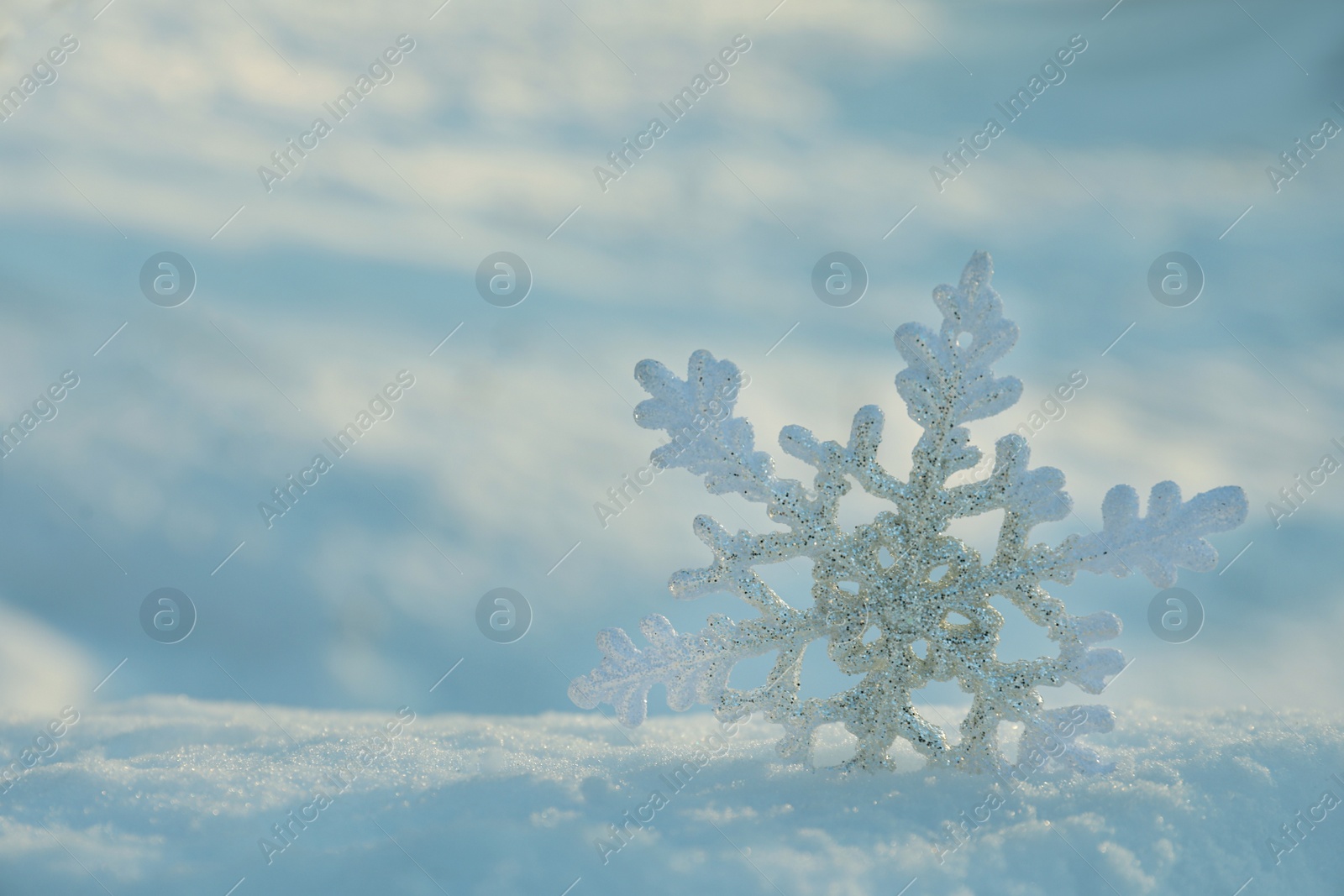 Photo of Beautiful decorative snowflake in white snow, outdoors. Space for text