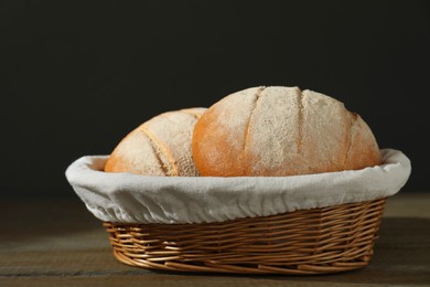 Photo of Wicker basket with fresh bread on wooden table