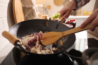 Photo of Man stirring cut vegetables in frying pan, closeup