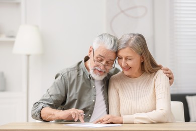 Senior couple signing Last Will and Testament indoors