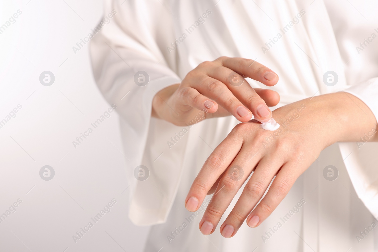 Photo of Woman applying luxury cosmetic cream onto hand on white background, closeup