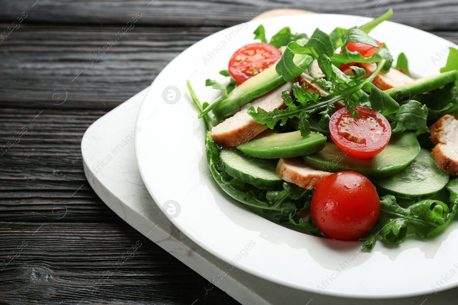 Photo of Delicious fresh chicken salad served on black wooden table, closeup