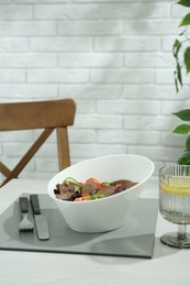 Delicious salad with beef tongue and vegetables served on white wooden table indoors. Space for text