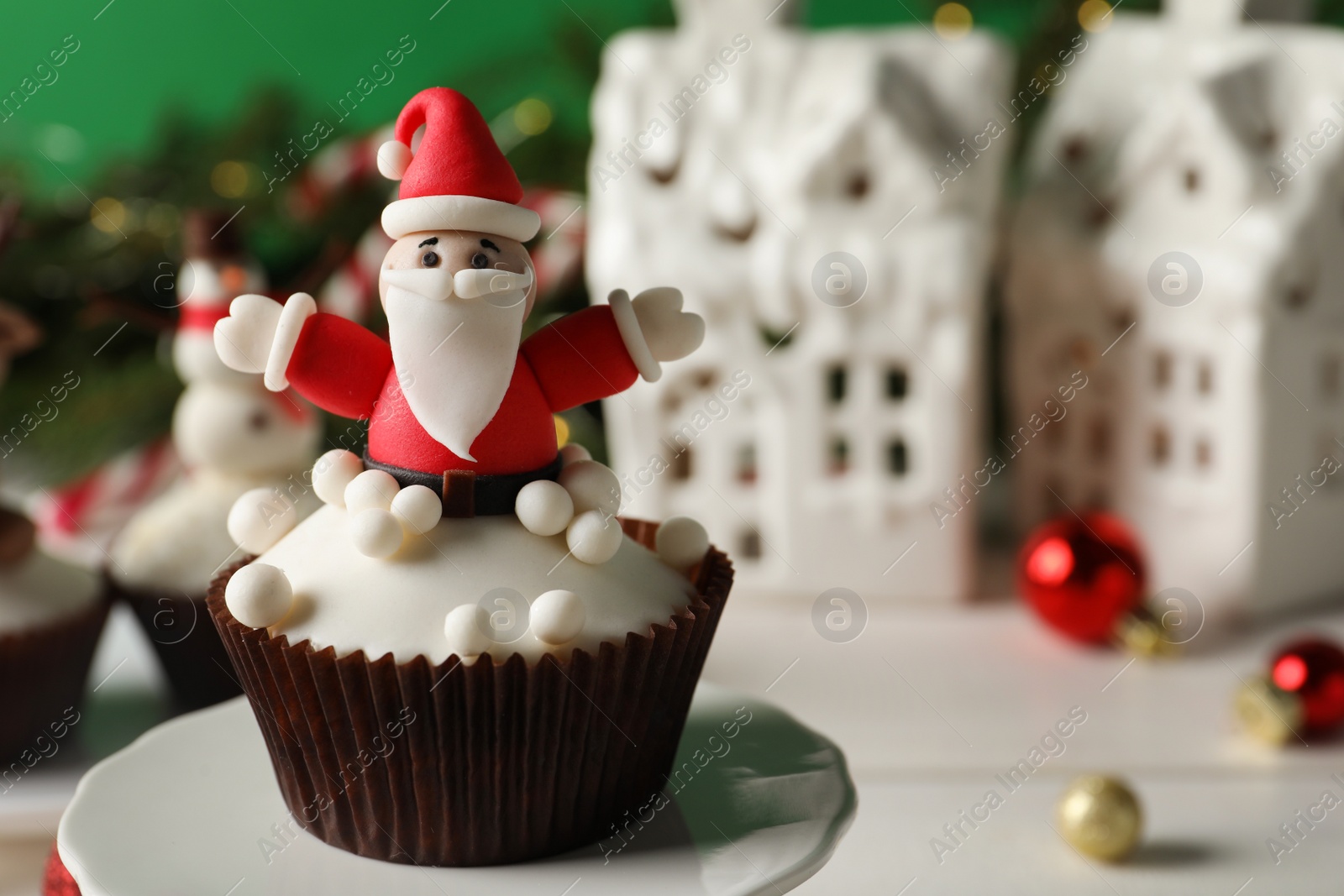 Photo of Tasty Christmas cupcake with Santa Claus figure on stand, closeup view. Space for text