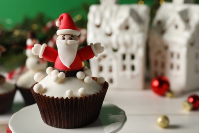Photo of Tasty Christmas cupcake with Santa Claus figure on stand, closeup view. Space for text