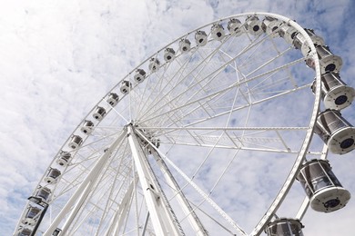 Beautiful Ferris wheel against cloudy sky, low angle view