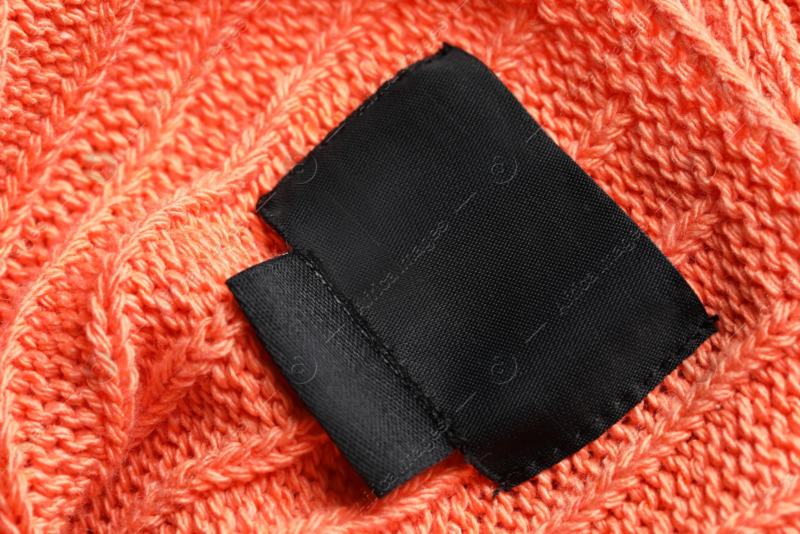 Photo of Black clothing labels on orange garment, top view