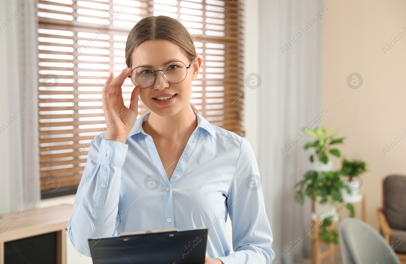 Photo of Professional psychotherapist with glasses and clipboard in office