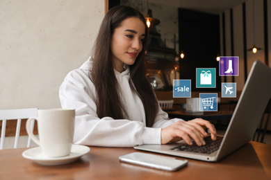 Image of Young woman using laptop at table in cafe. Online shopping