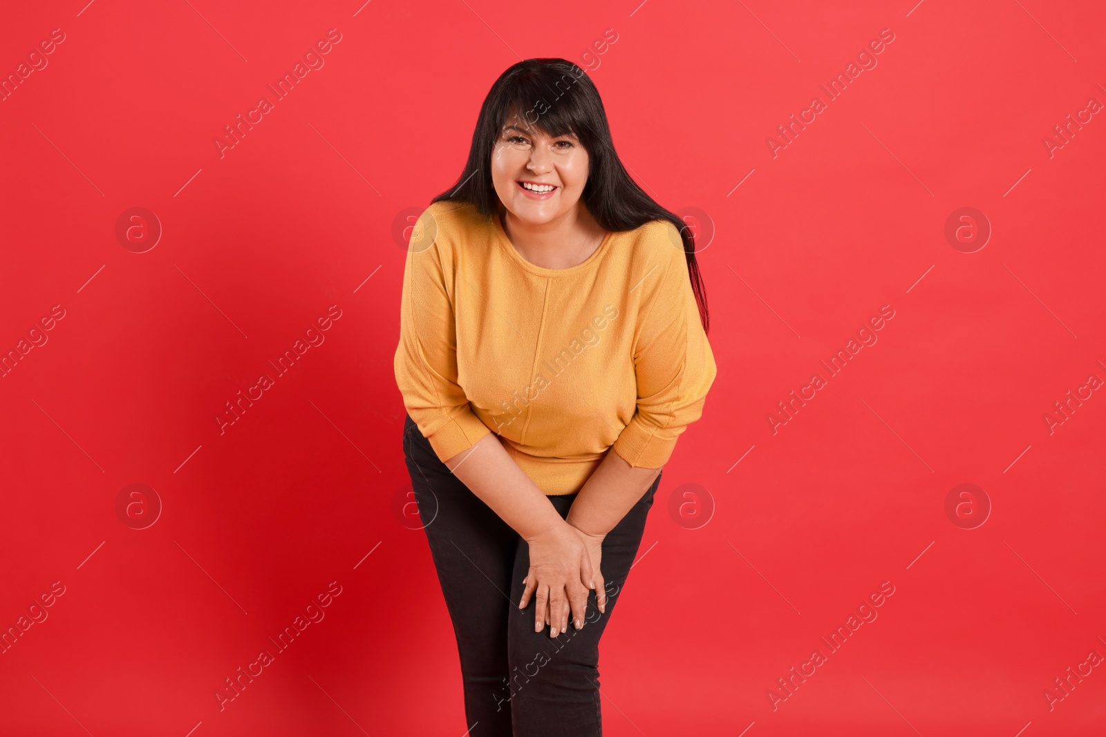 Photo of Beautiful overweight mature woman with charming smile on red background