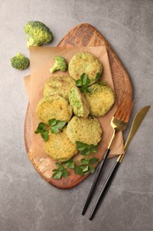 Delicious vegan cutlets with broccoli, parsley and cutlery on light gray table, flat lay