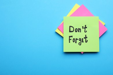 Photo of Paper note with phrase Don' t Forget on blue background, top view. Space for text