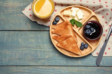 Photo of Tasty toasts served with butter and blueberries on light blue wooden table, flat lay. Space for text