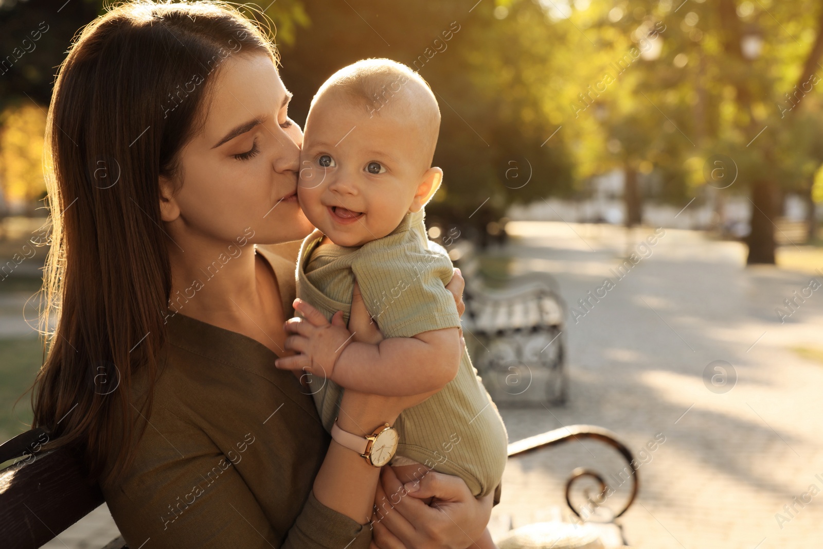 Photo of Young mother with her cute baby on bench in park