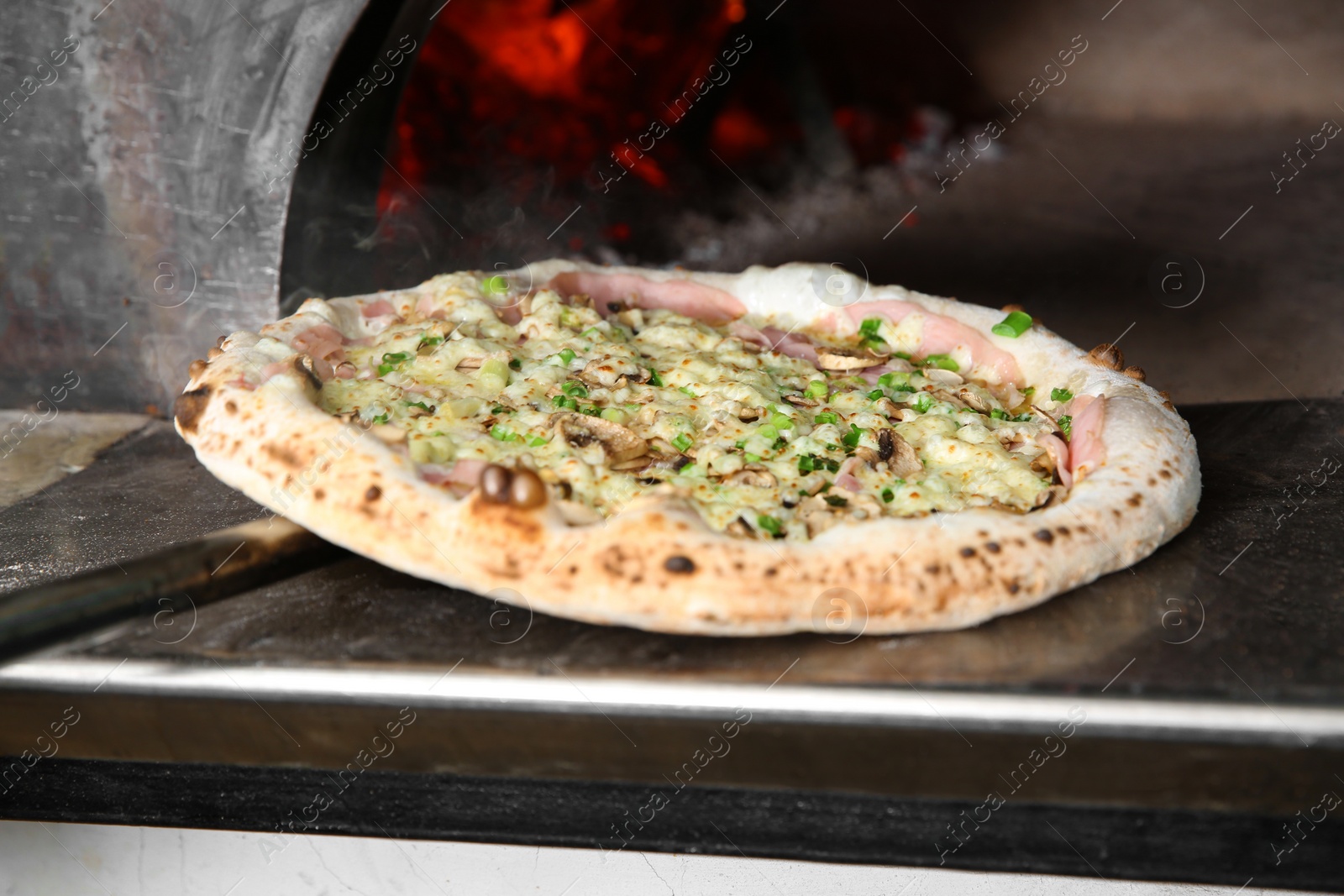 Photo of Taking out tasty pizza from oven in restaurant kitchen