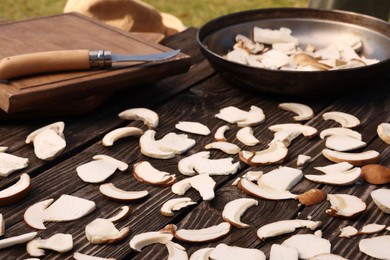 Photo of Slices of mushrooms on wooden table outdoors