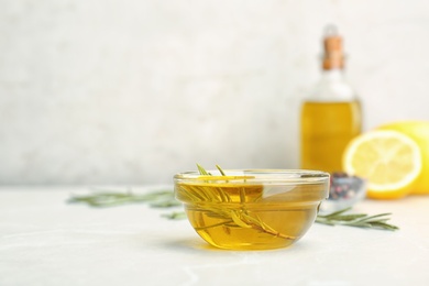 Photo of Bowl with essential rosemary oil on table