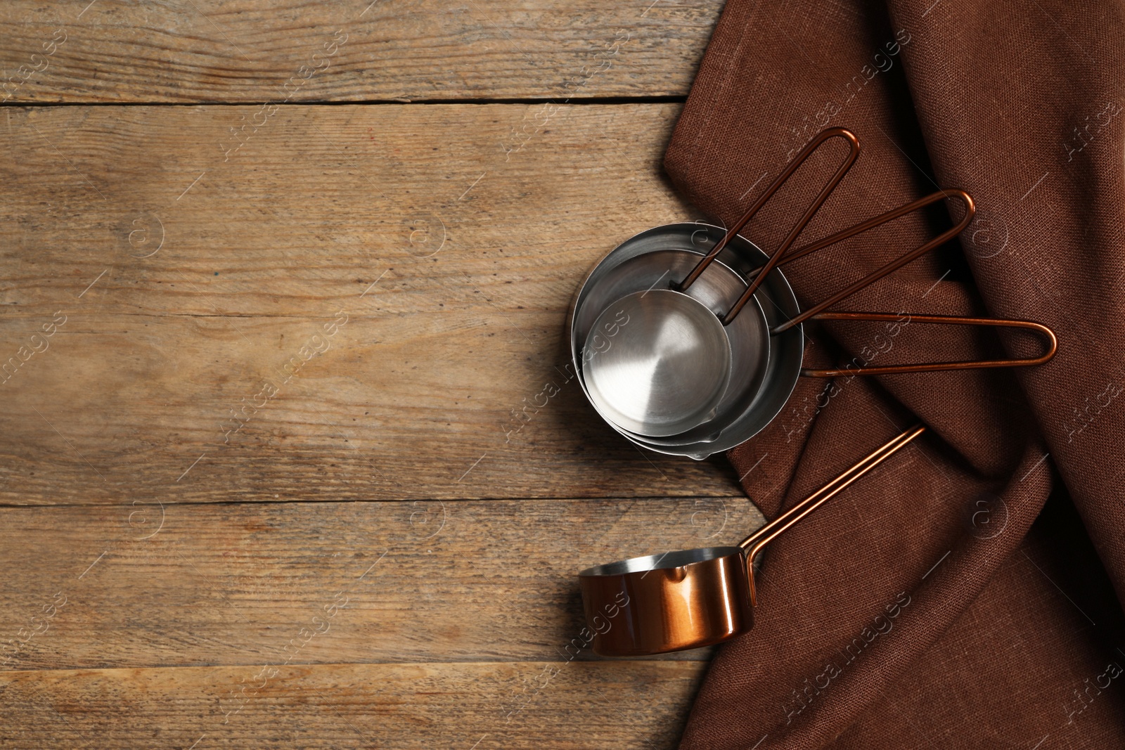 Photo of Saucepans and brown cloth on wooden table, flat lay with space for text. Cooking utensils