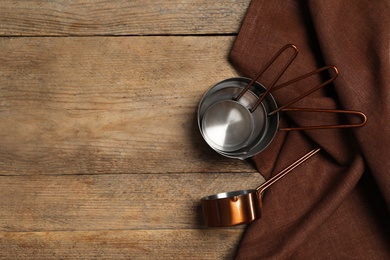 Saucepans and brown cloth on wooden table, flat lay with space for text. Cooking utensils