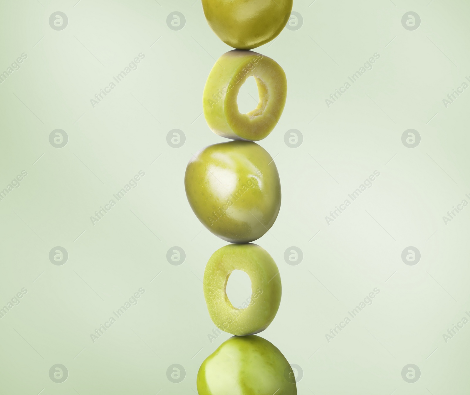 Image of Cut and whole olives on dusty light green background