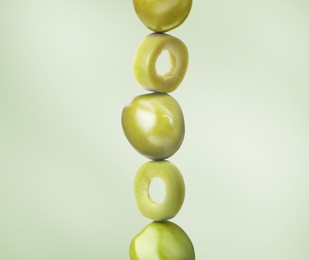 Cut and whole olives on dusty light green background