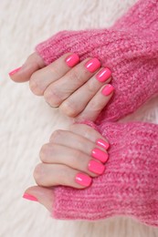 Woman showing her manicured hands with pink nail polish on faux fur mat, closeup