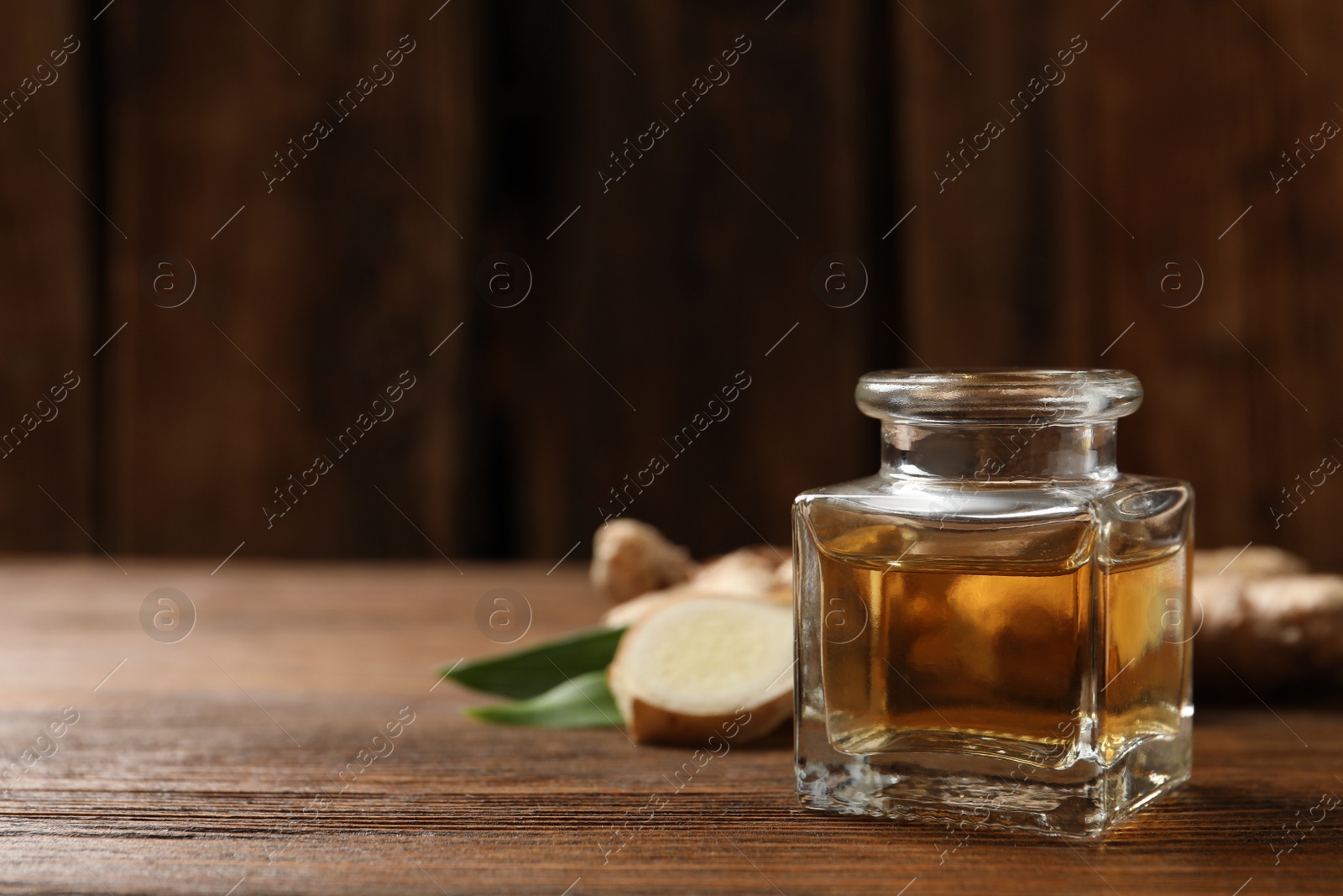 Photo of Ginger essential oil in bottle on wooden table. Space for text