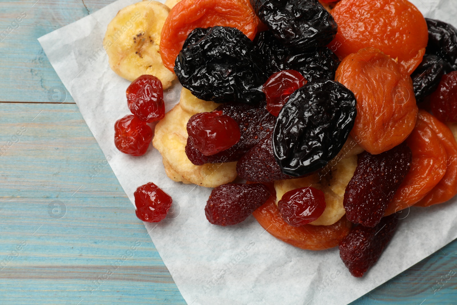 Photo of Mix of delicious dried fruits on light blue wooden table, closeup