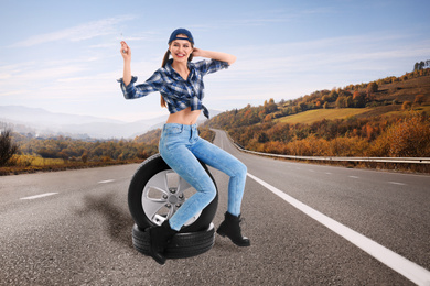 Image of Young woman with car tires on asphalt road outdoors