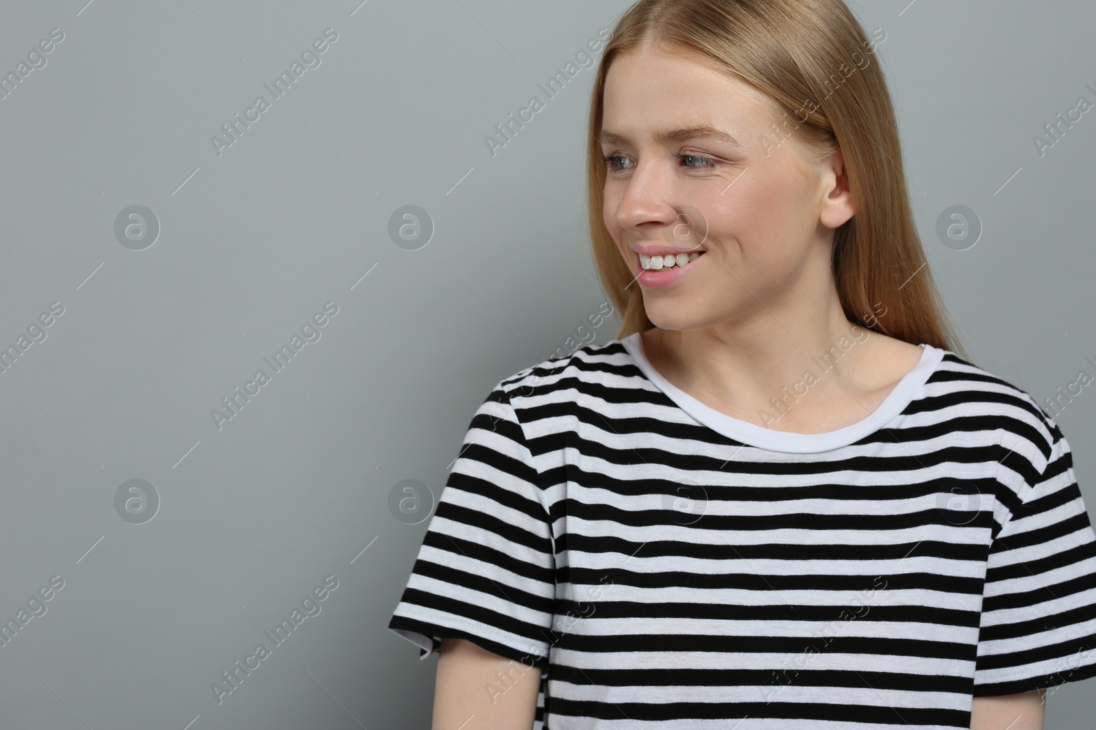 Photo of Portrait of beautiful young woman in striped t-shirt on grey background. Space for text