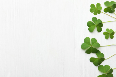 Photo of Clover leaves on white wooden table, flat lay with space for text. St. Patrick's Day symbol