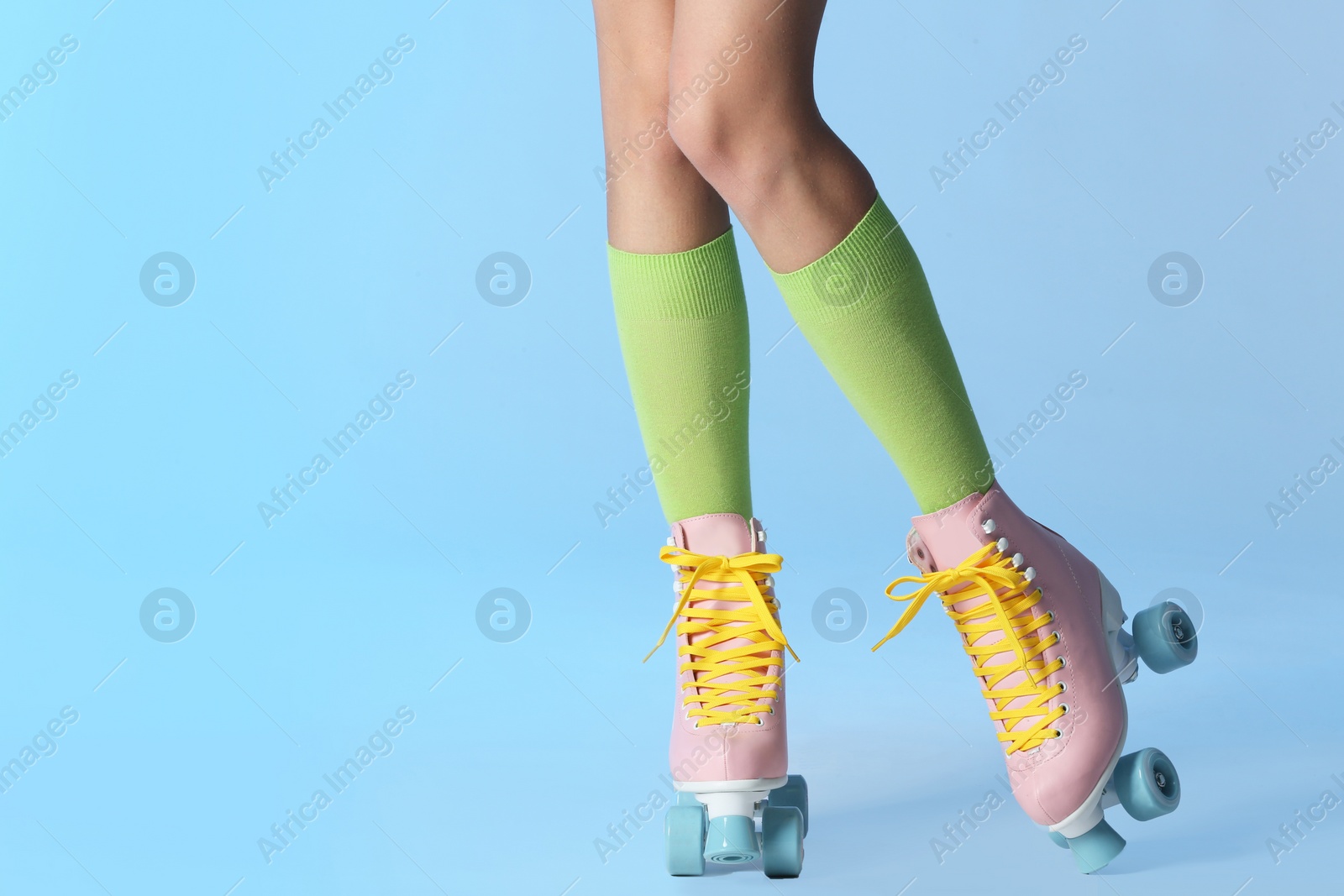 Photo of Woman with vintage roller skates on color background, closeup. Space for text