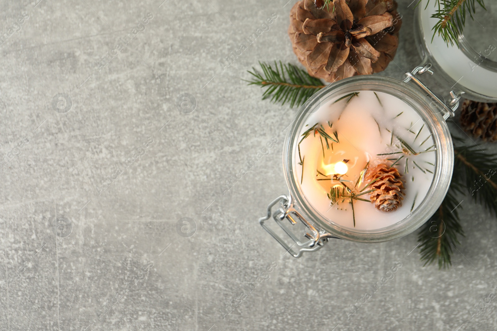 Photo of Burning scented conifer candle and Christmas decor on grey table, flat lay. Space for text