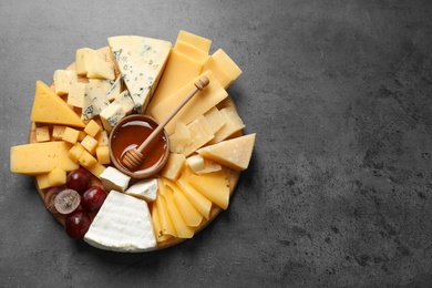 Different types of delicious cheese and snacks on served grey table, top view. Space for text