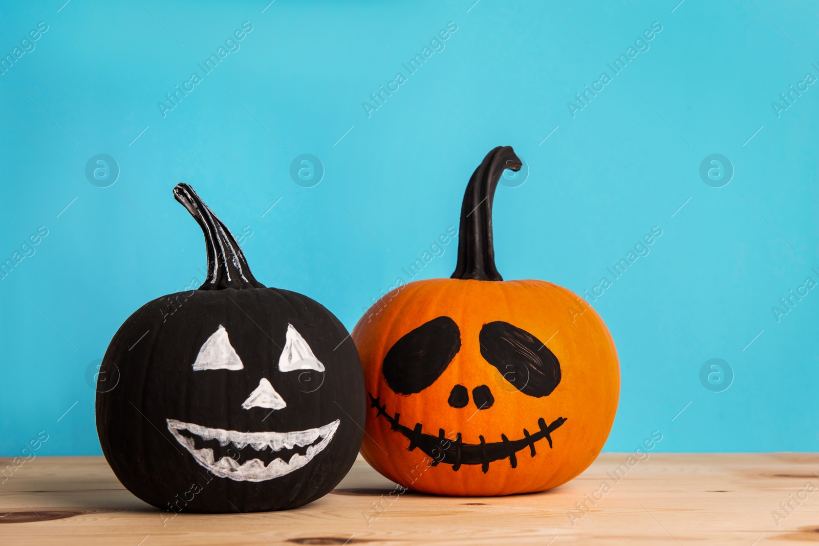 Photo of Halloween celebration. Pumpkins with spooky drawn faces on wooden table