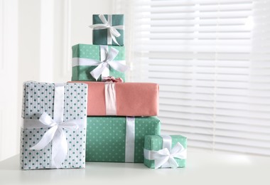 Photo of Heap of wrapped gift boxes on white table, space for text. Happy holiday