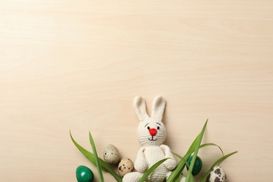 Flat lay composition of Easter bunny toy and eggs on wooden background, space for text