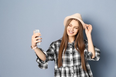 Photo of Young beautiful woman taking selfie against grey background