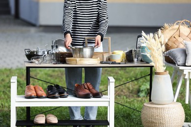 Photo of Woman near tables with different stuff on garage sale outdoors