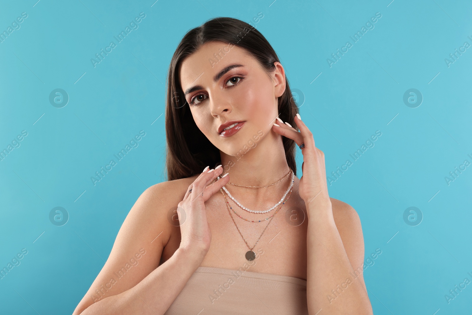 Photo of Beautiful woman with elegant jewelry on light blue background