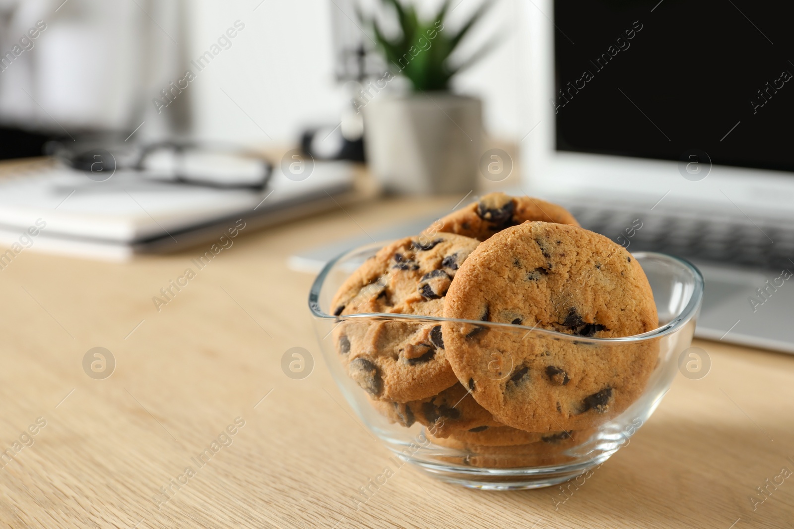 Photo of Chocolate chip cookies on wooden table at workplace. Space for text