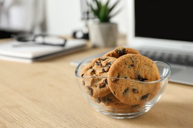 Chocolate chip cookies on wooden table at workplace. Space for text