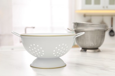 Photo of Different clean colanders on white marble table in kitchen